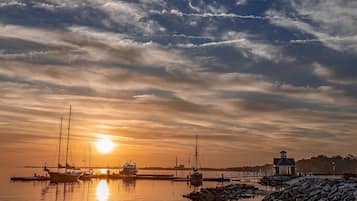 Un puerto tranquilo con barcos y un faro al atardecer.