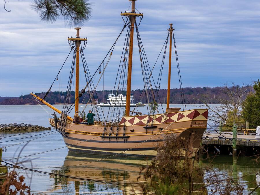Um navio histórico atracado em cais, com uma orla arborizada ao fundo.