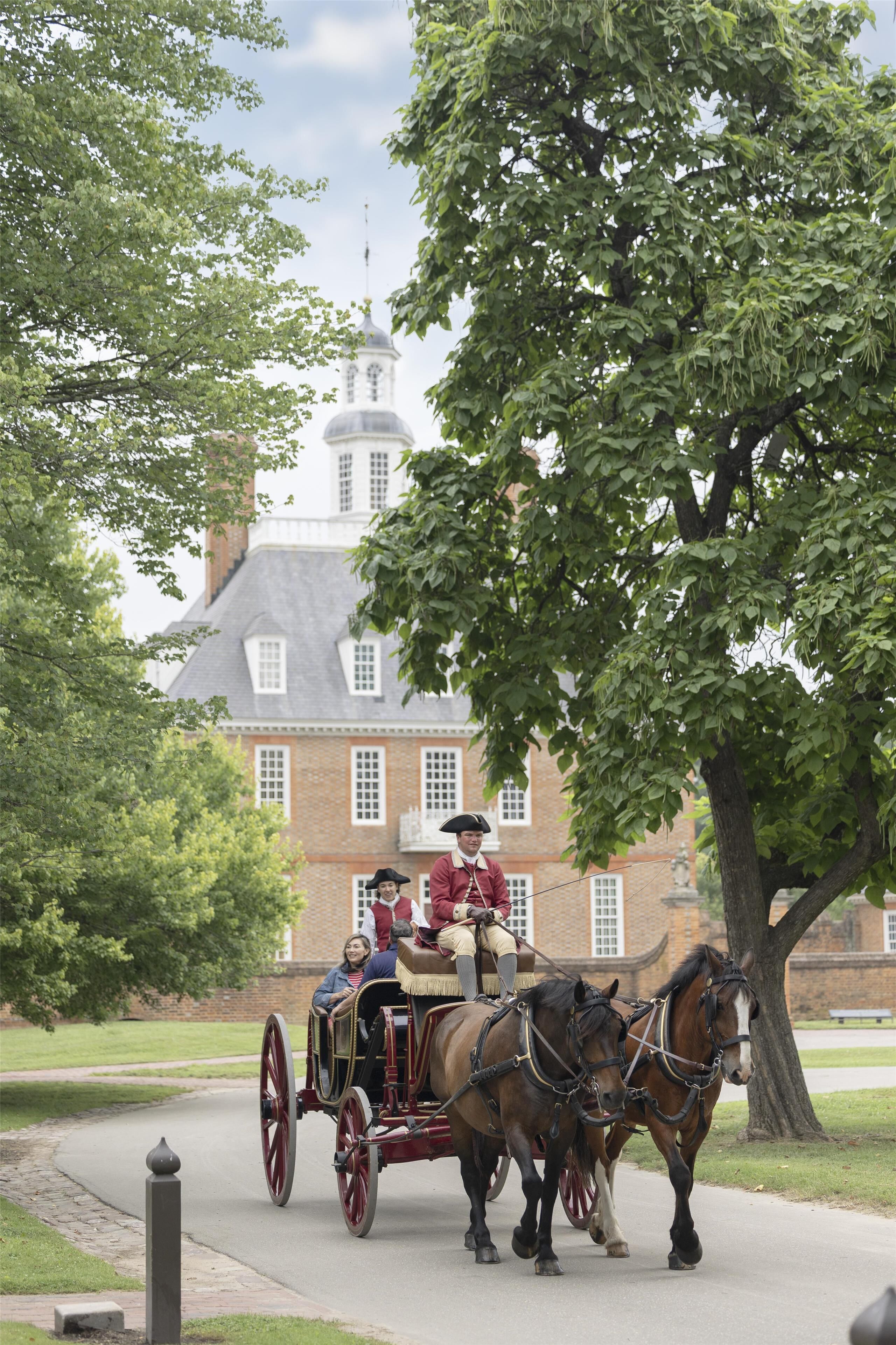 A horse-drawn carriage with passengers and horses on a paved path.