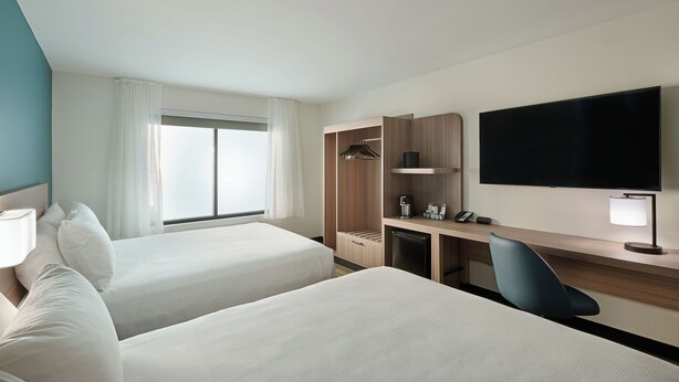A hotel room with two beds, a desk, a TV, a wardrobe, and a window with curtains. - Hyatt Select Williamsburg (Williamsburg)