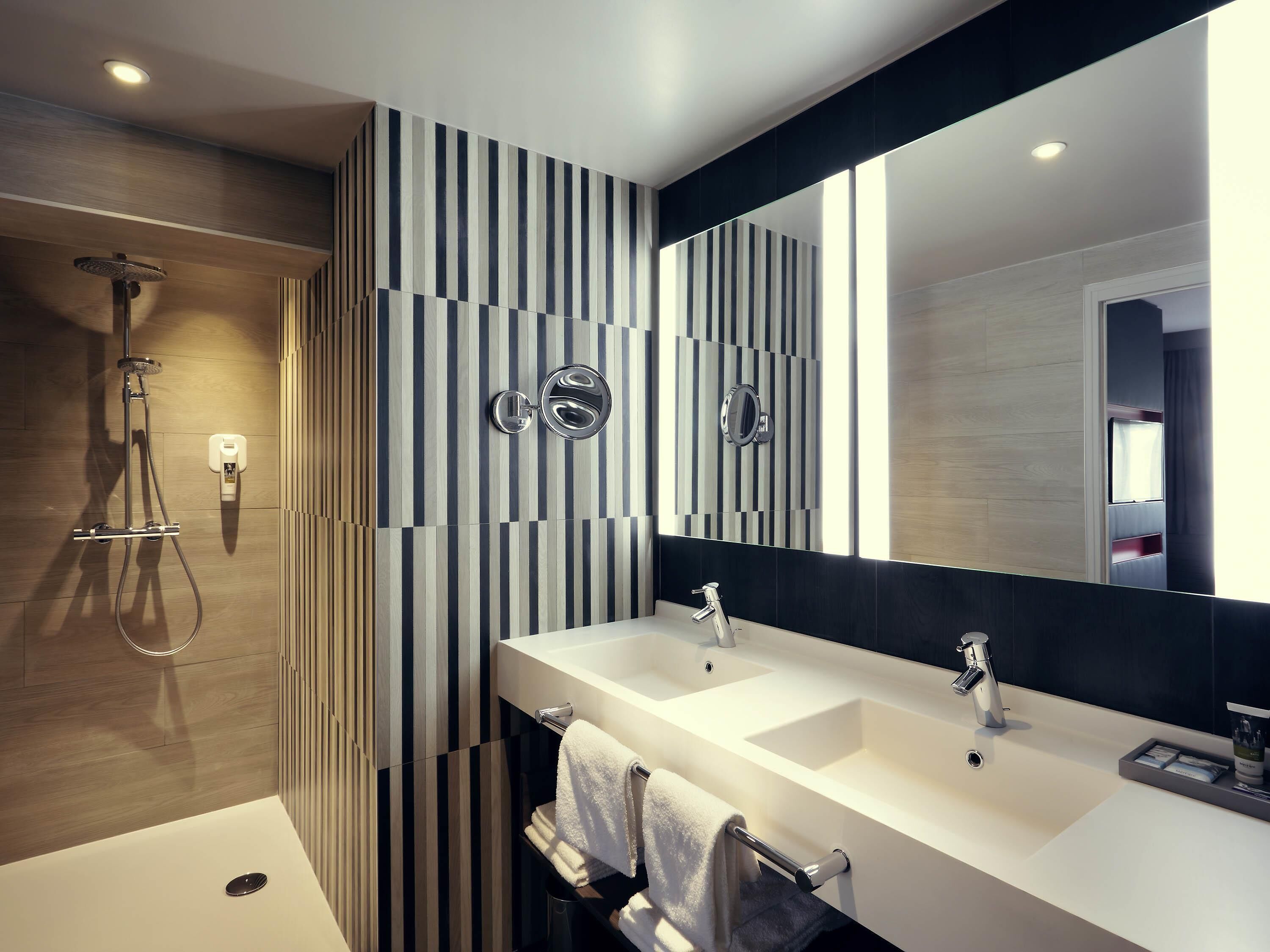 A modern bathroom with a shower, two sinks, and a large mirror.