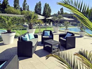 Outdoor seating with potted plants, a pool, and a building in the background. - Mercure Orange Centre (Orange)