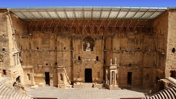 Un antiguo anfiteatro con asientos de piedra y una estatua central.