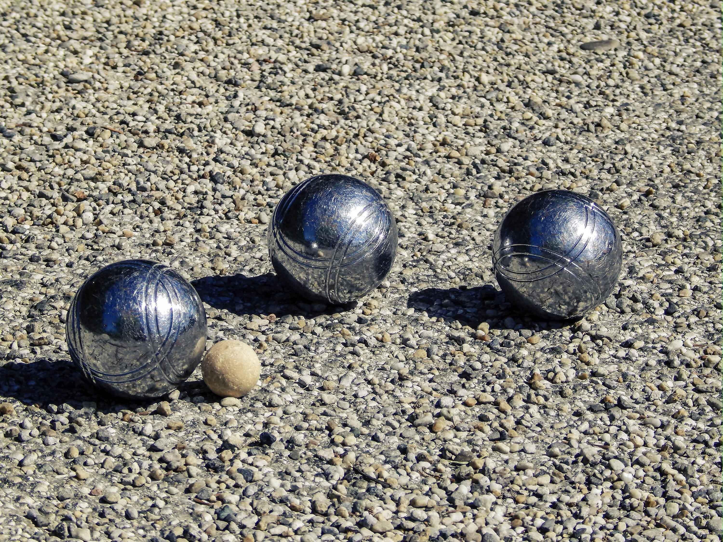 Three metallic balls on a gravel surface.