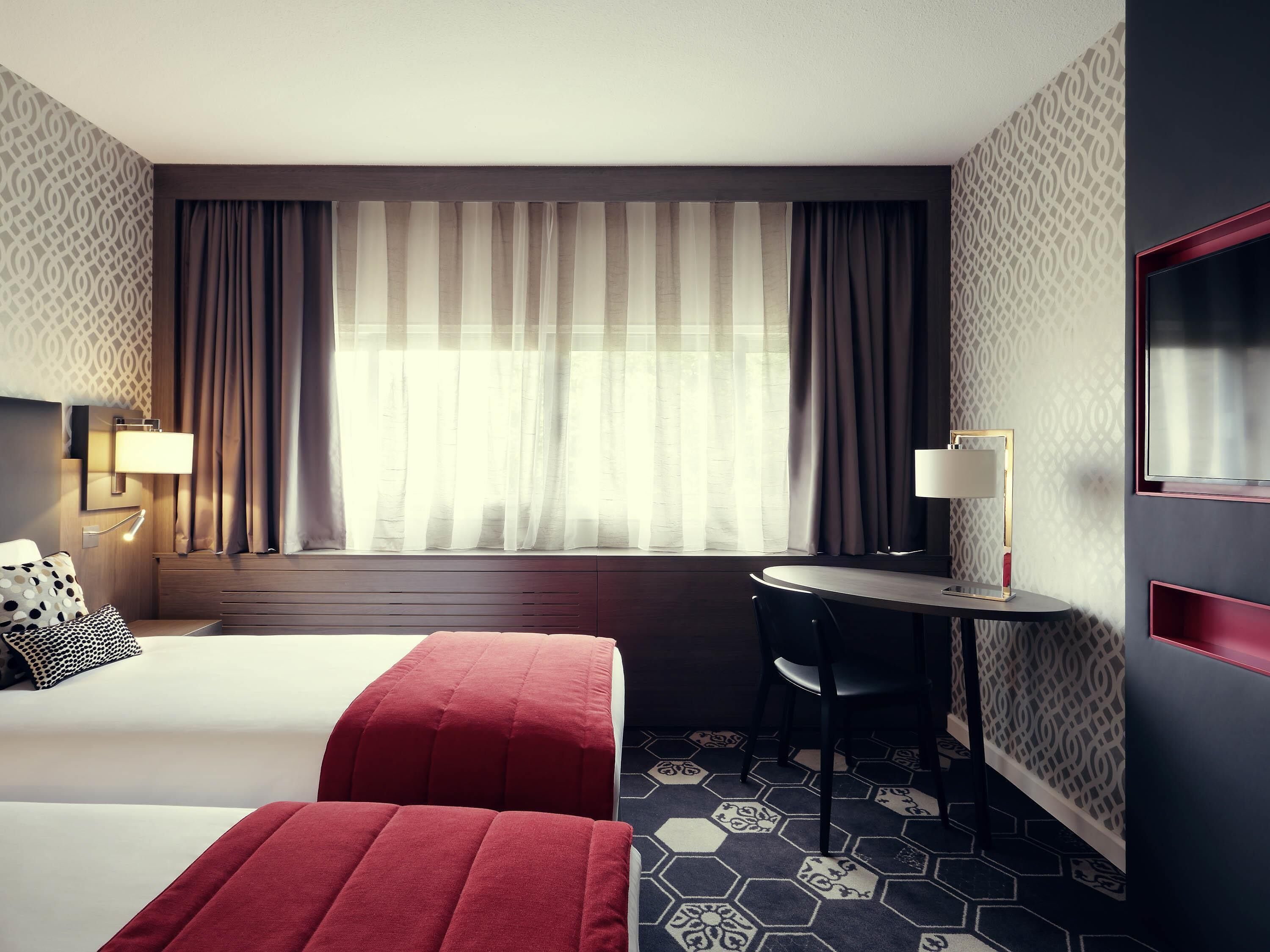 Habitación de hotel con dos camas, un escritorio y una silla.