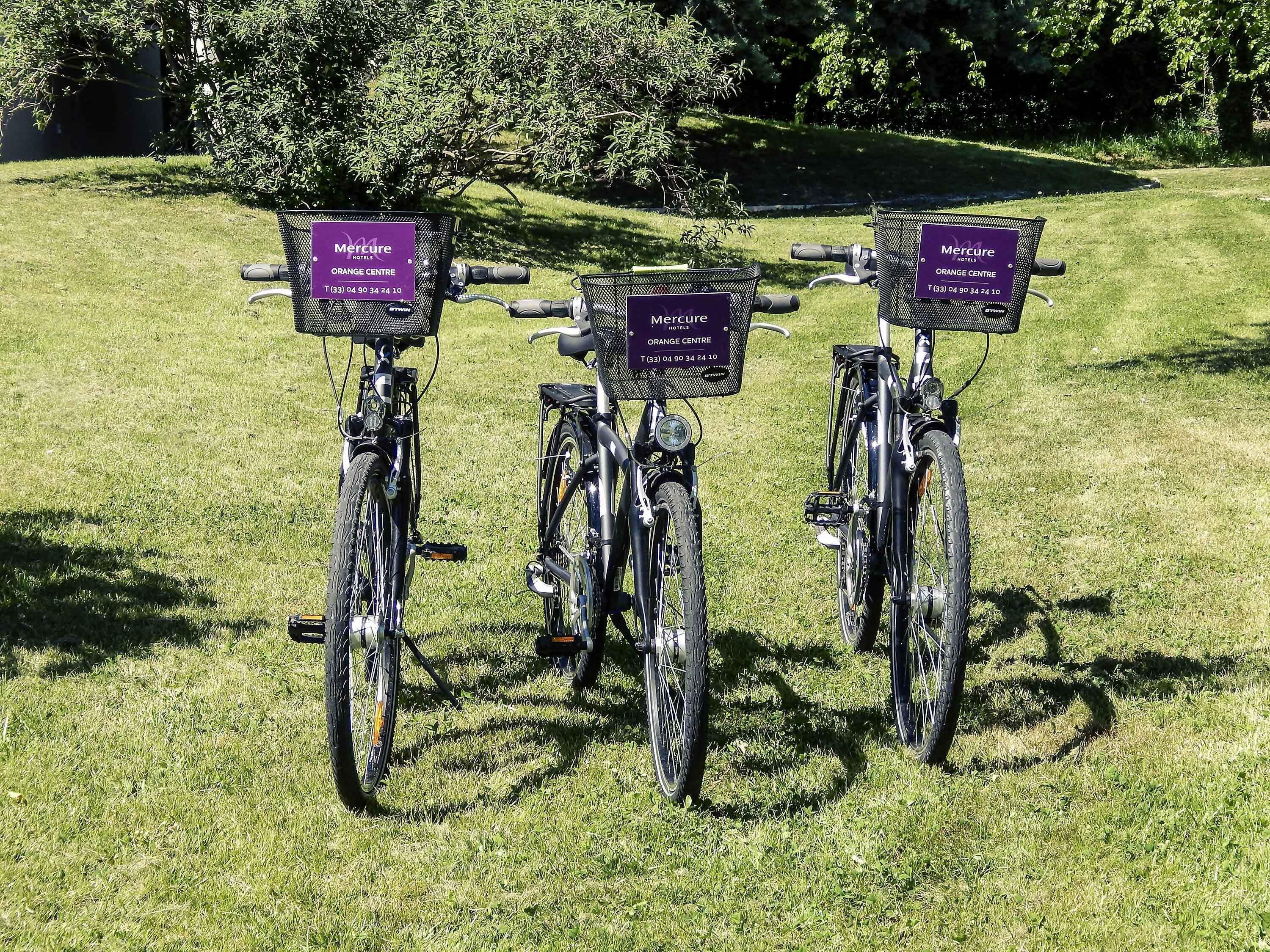 Three bicycles parked on grass with attached Mercure hotel signs.