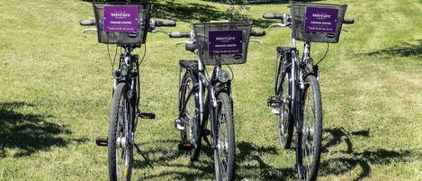 Three bicycles parked on grass with attached Mercure hotel signs.