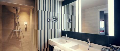 A modern bathroom with a shower, two sinks, and a large mirror.