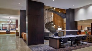 A modern lobby with a reception desk, seating area, and a staircase with a wooden finish. - Sheraton Ottawa Hotel (Ottawa)