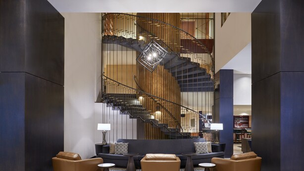 A modern lobby with a central staircase, leather seating, and a patterned carpet. - Sheraton Ottawa Hotel (Ottawa)