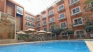 An indoor swimming pool with a glass ceiling, surrounded by balconies with plants and umbrellas. - Holiday Inn Express Tecnológico Monterrey by IHG (Monterrey)