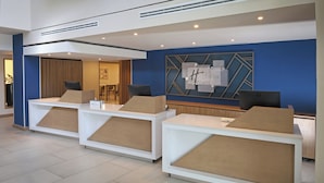 A reception area with three white reception desks, a blue accent wall, and a geometric wall decoration. - Holiday Inn Express Tecnológico Monterrey by IHG (Monterrey)