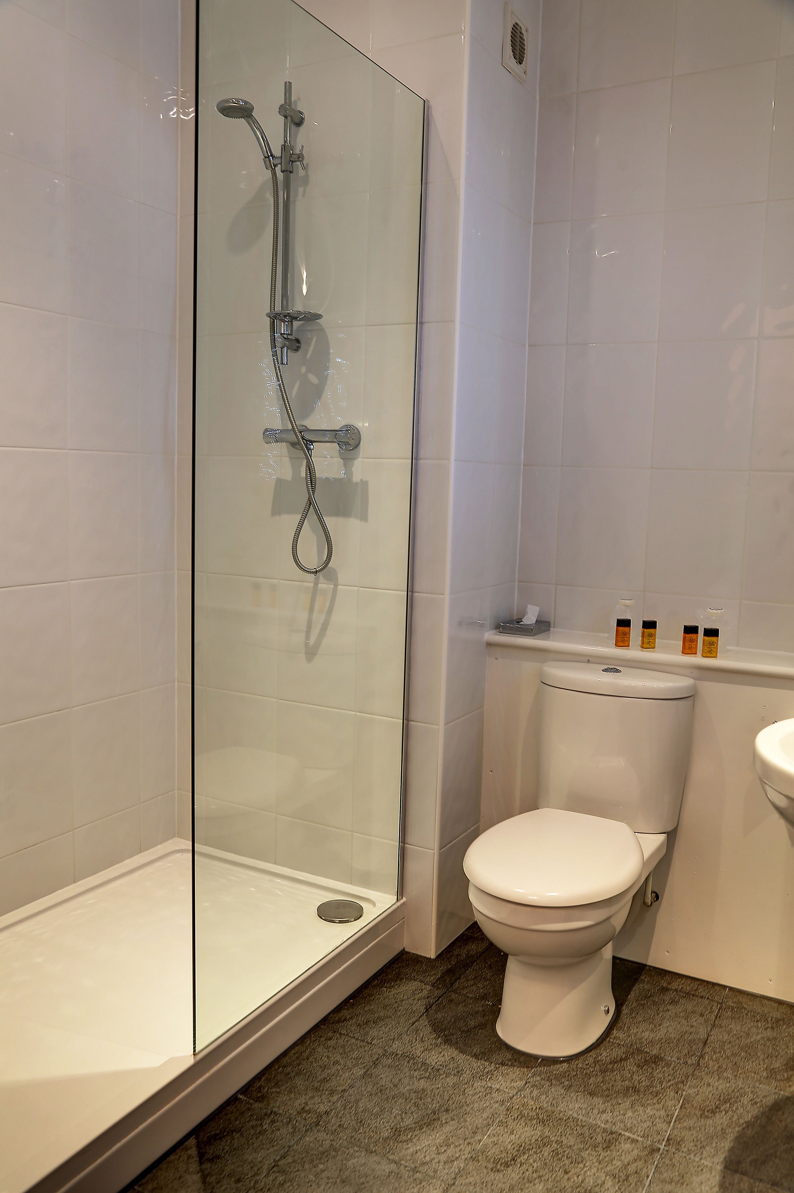 Un baño con ducha de vidrio, inodoro blanco y lavamanos.