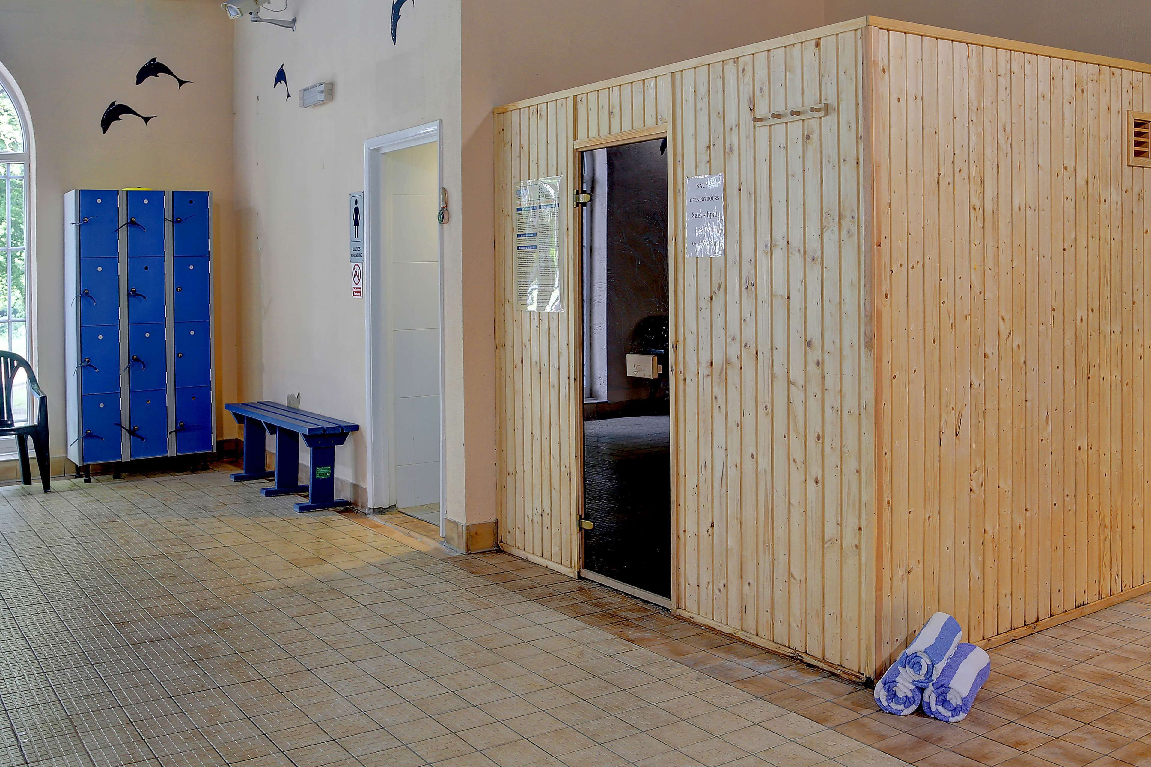 A room with a wooden cabinet, a bench, and a pair of towels on the floor.