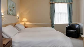 Habitación de hotel con una cama grande, una silla, una lámpara y un cuadro en la pared.