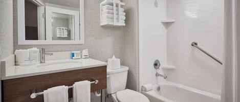 A modern bathroom with a vanity, toilet, and bathtub.