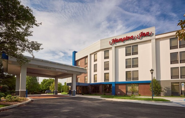 Een Hampton Inn hotel met een duidelijke ingang, een tankstation en een parkeerplaats.