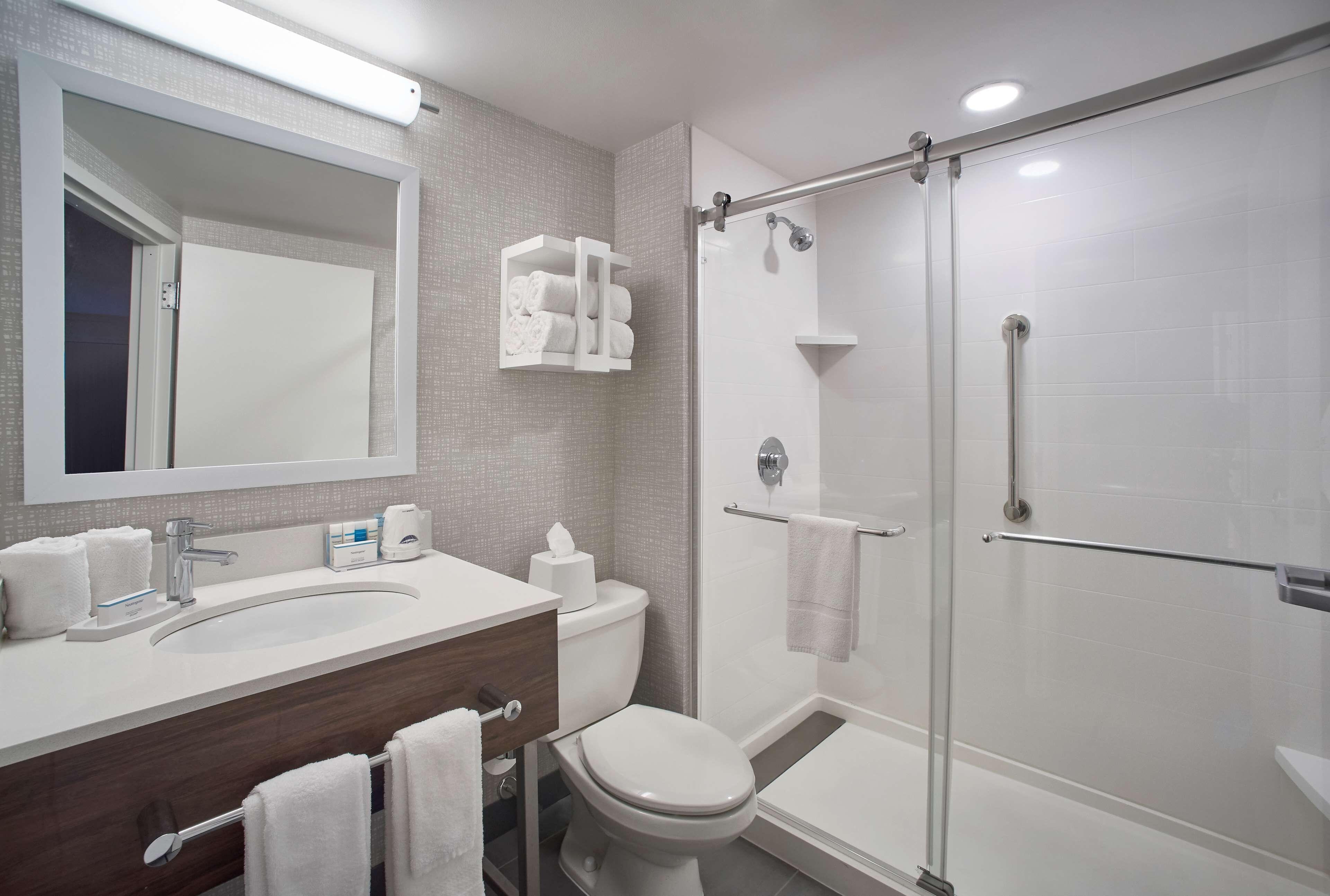 Un baño moderno con lavamanos, inodoro y ducha con mampara de vidrio.