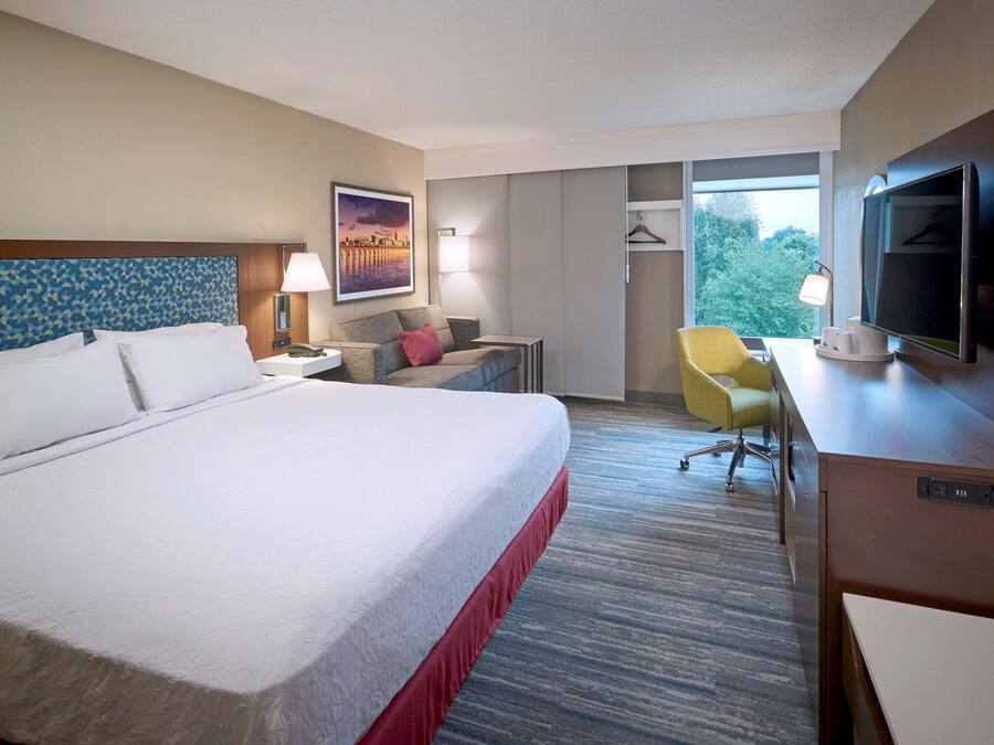 Une chambre d’hôtel avec un grand lit, un bureau avec une télévision, une chaise et une armoire.