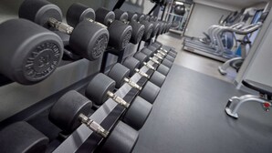 A gym with rows of black dumbbells on a rack, a treadmill, and a bench. - Hampton Inn by Hilton Harrisburg West (Mechanicsburg)