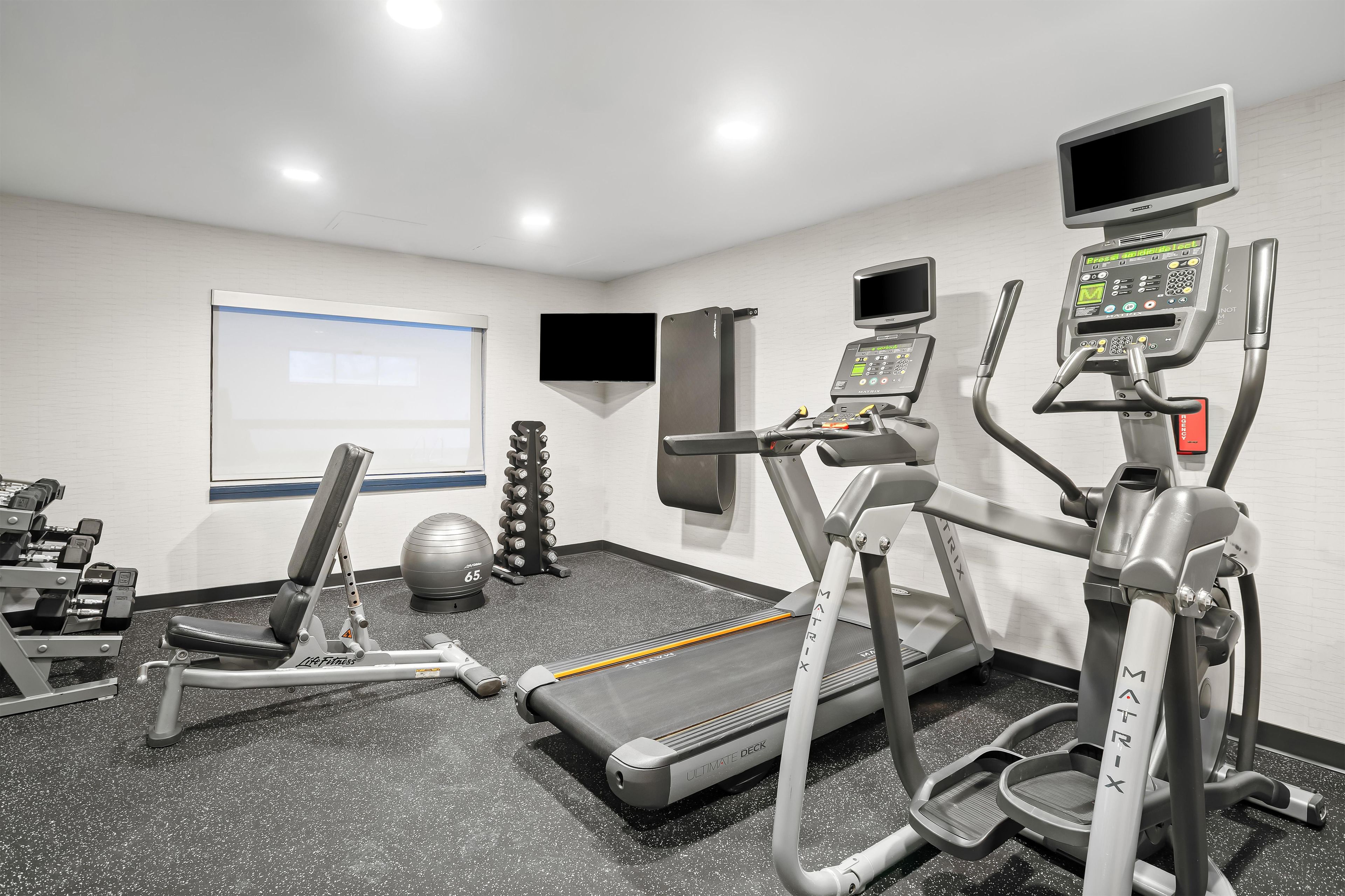 Academia com esteiras, aparelhos de musculação e remo.
