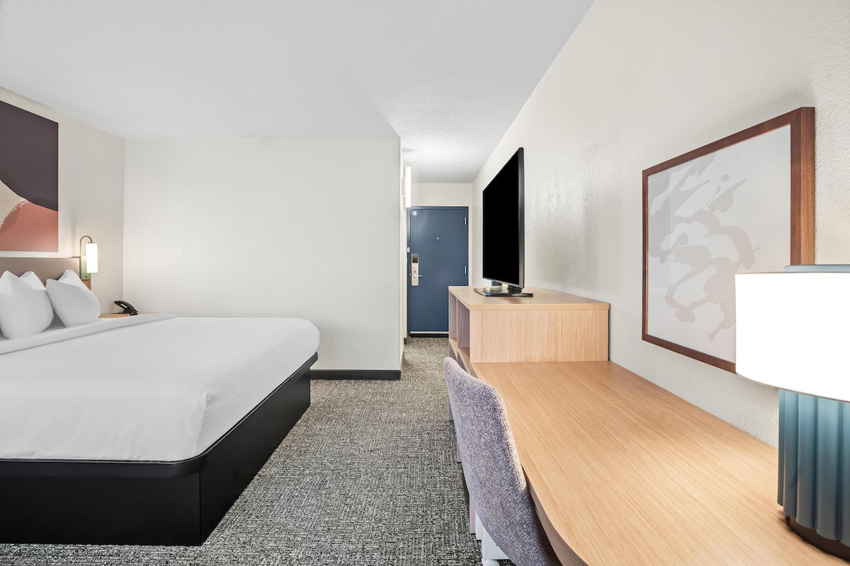 Une chambre d’hôtel équipée d’un lit, d’un bureau, d’une chaise, d’une télévision et d’une lampe.