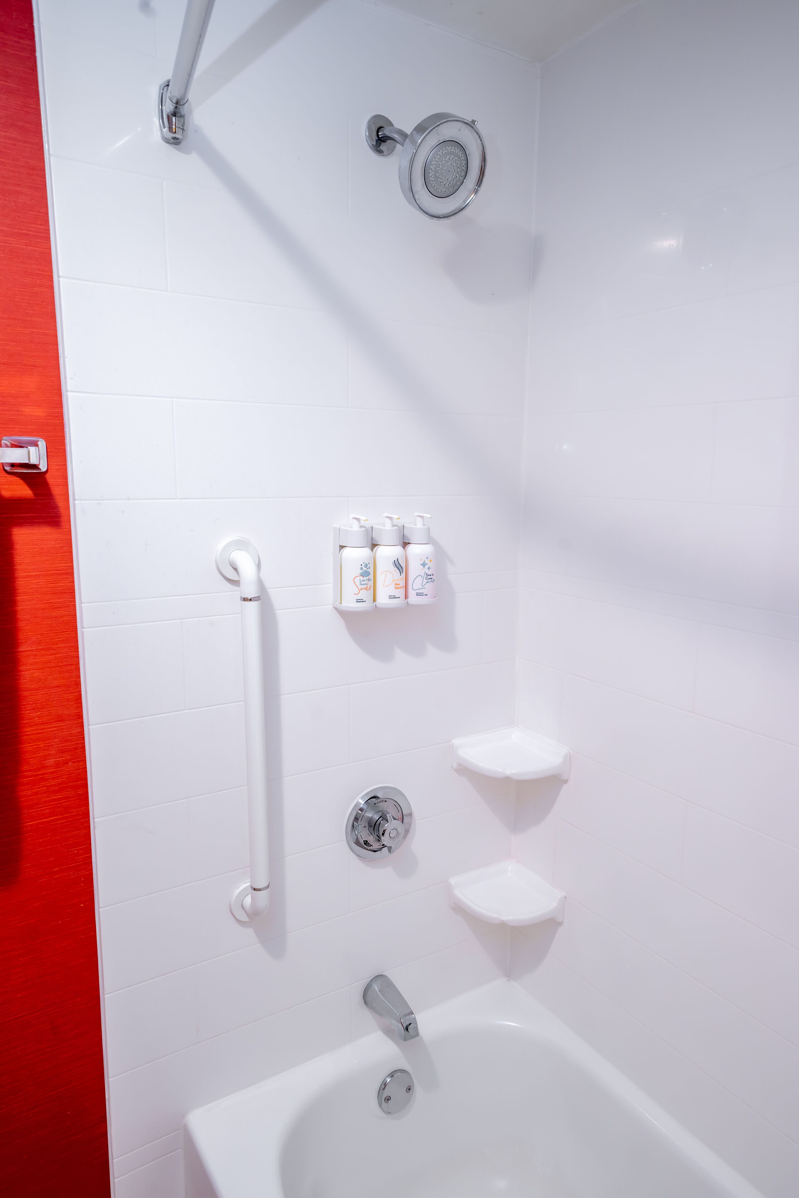 Un bagno moderno con una vasca da bagno bianca, una doccetta e una maniglia di sostegno.