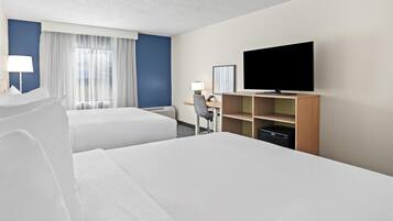 Une chambre d’hôtel avec deux lits, un bureau, une télévision et une fenêtre avec des rideaux.