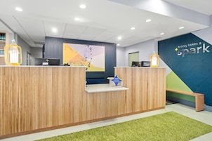 A reception desk with a wooden finish, a blue wall with the text 'It only takes a spark,' and a green carpet.