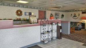 A reception area with a counter, a bulletin board, a fireplace, and a seating area with a couch. - Days Inn by Wyndham Morehead (Morehead)