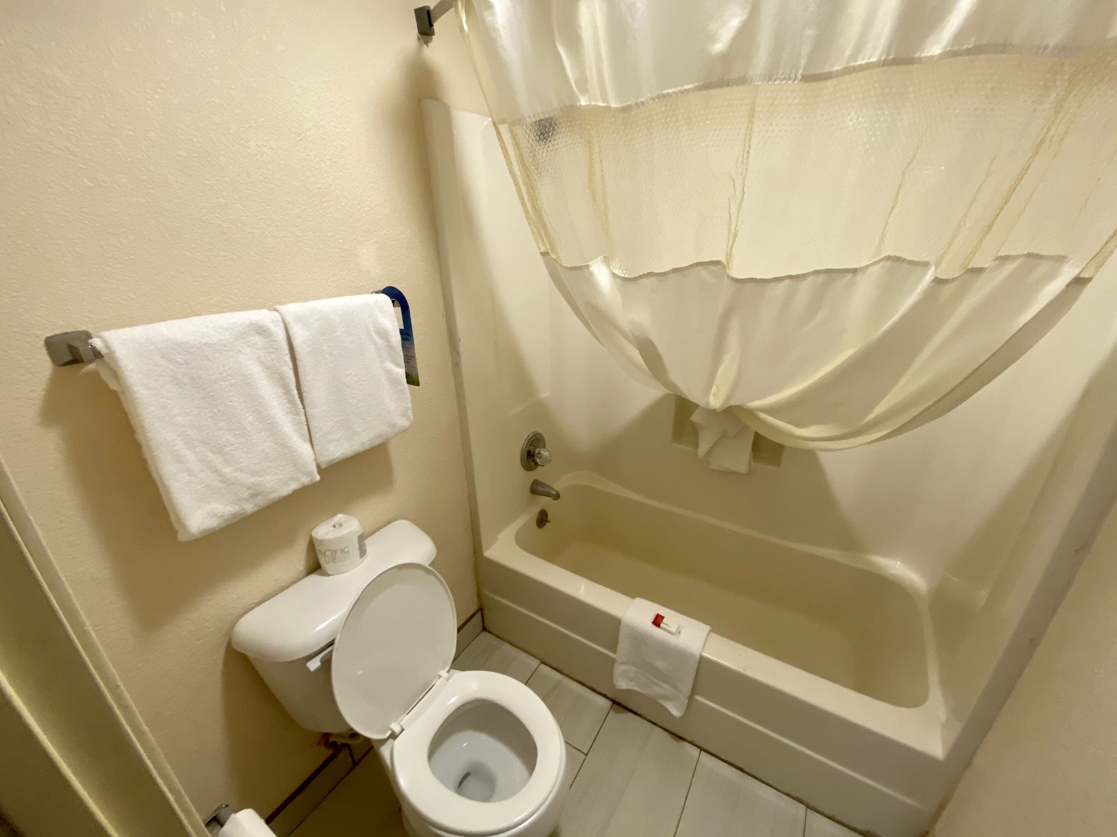 Une salle de bain avec des toilettes, une baignoire et un rideau de douche.