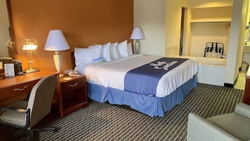 Een hotelkamer met een bed, bureau, stoel en een badkamer zichtbaar door een open deur.