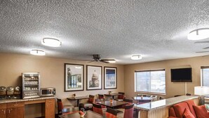 Habitación de hotel con kitchenette, comedor y zona de estar con sofá y sillones.