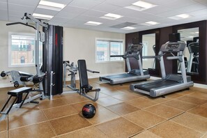 Un gimnasio con equipo de ejercicio, cinta de correr y bicicleta estática.