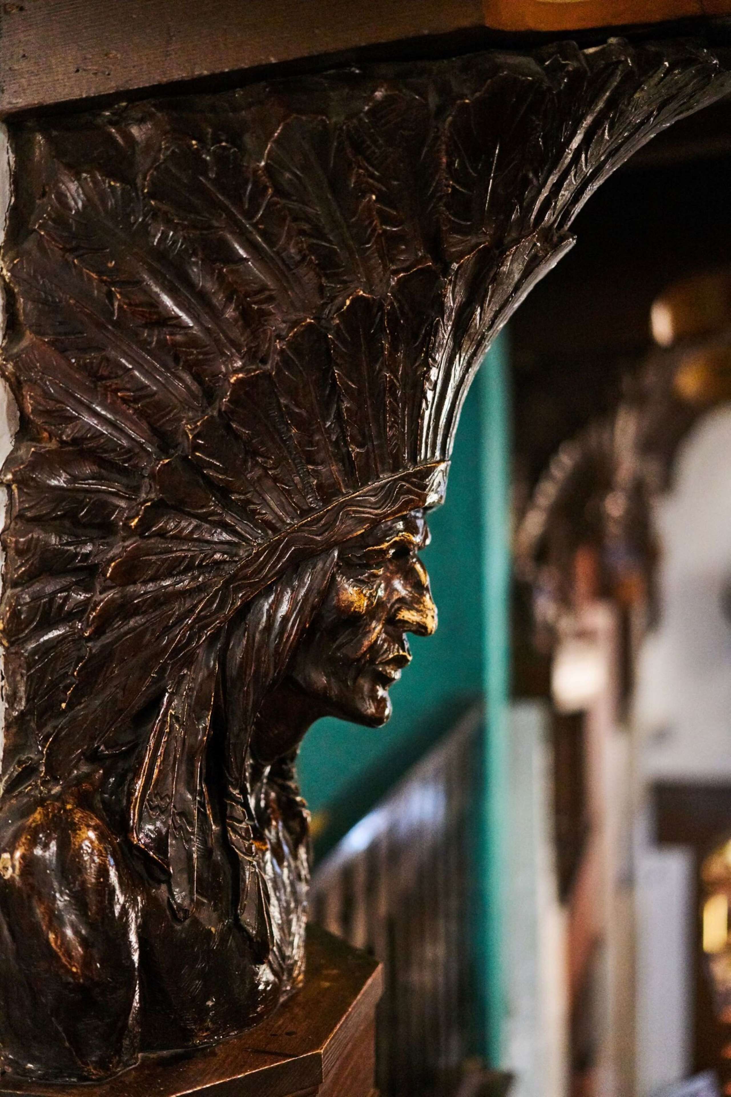 A detailed wooden carving of a leaf and a human profile.
