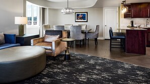 Una sala moderna con sofá, reposapiés y zona de comedor con sillas.