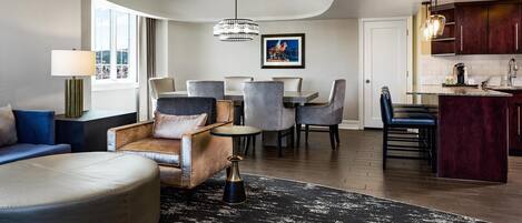 Una sala moderna con sofá, reposapiés y zona de comedor con sillas.