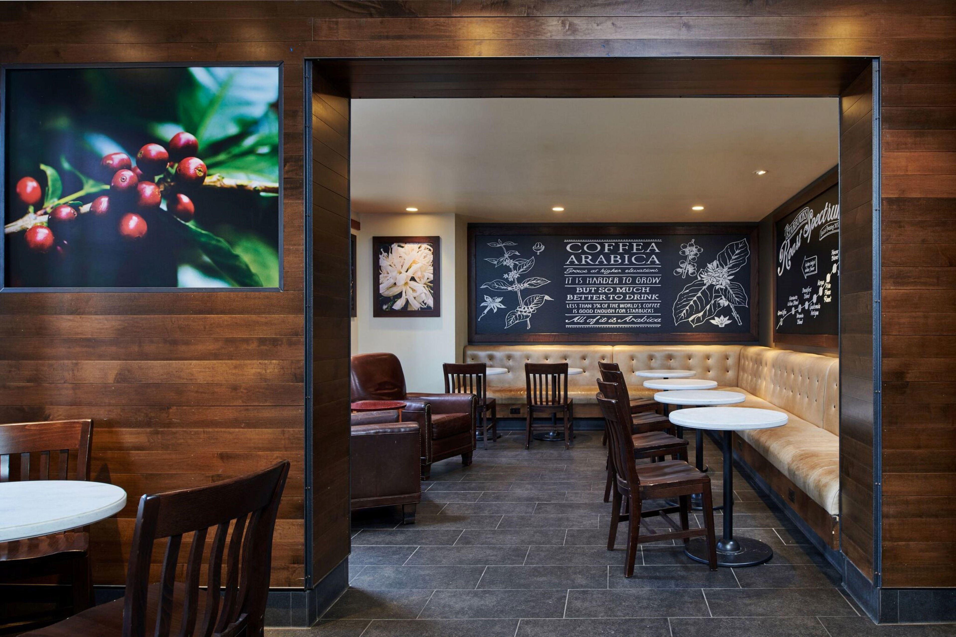 Ein Café-Interieur mit einer Sitzgelegenheit, Tischen und einer Wand mit Kaffeegrafiken.