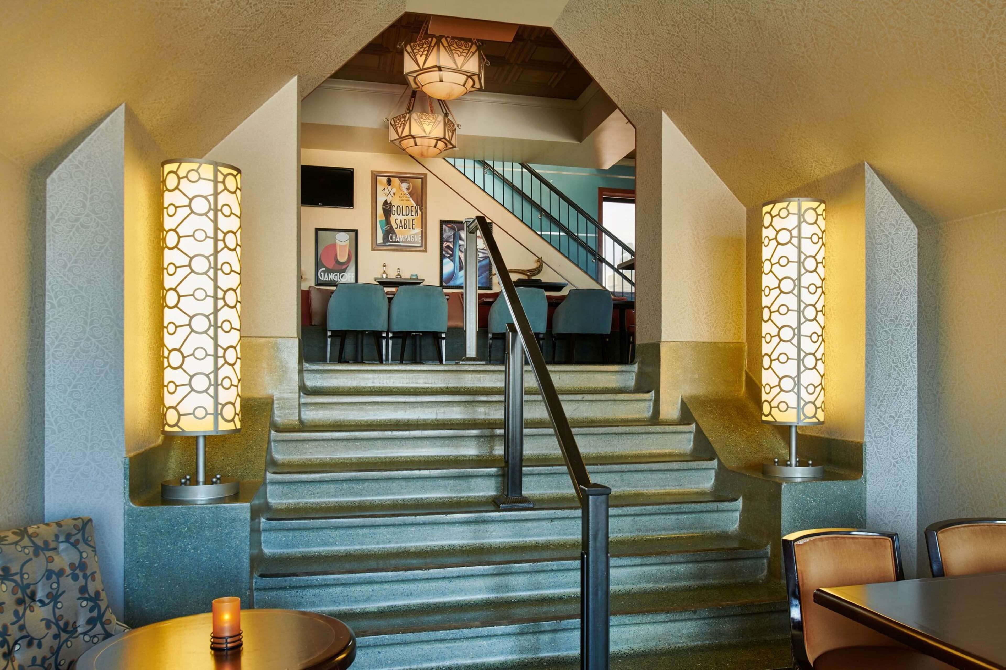 A staircase leading to a dining area with patterned lamps and a chandelier.