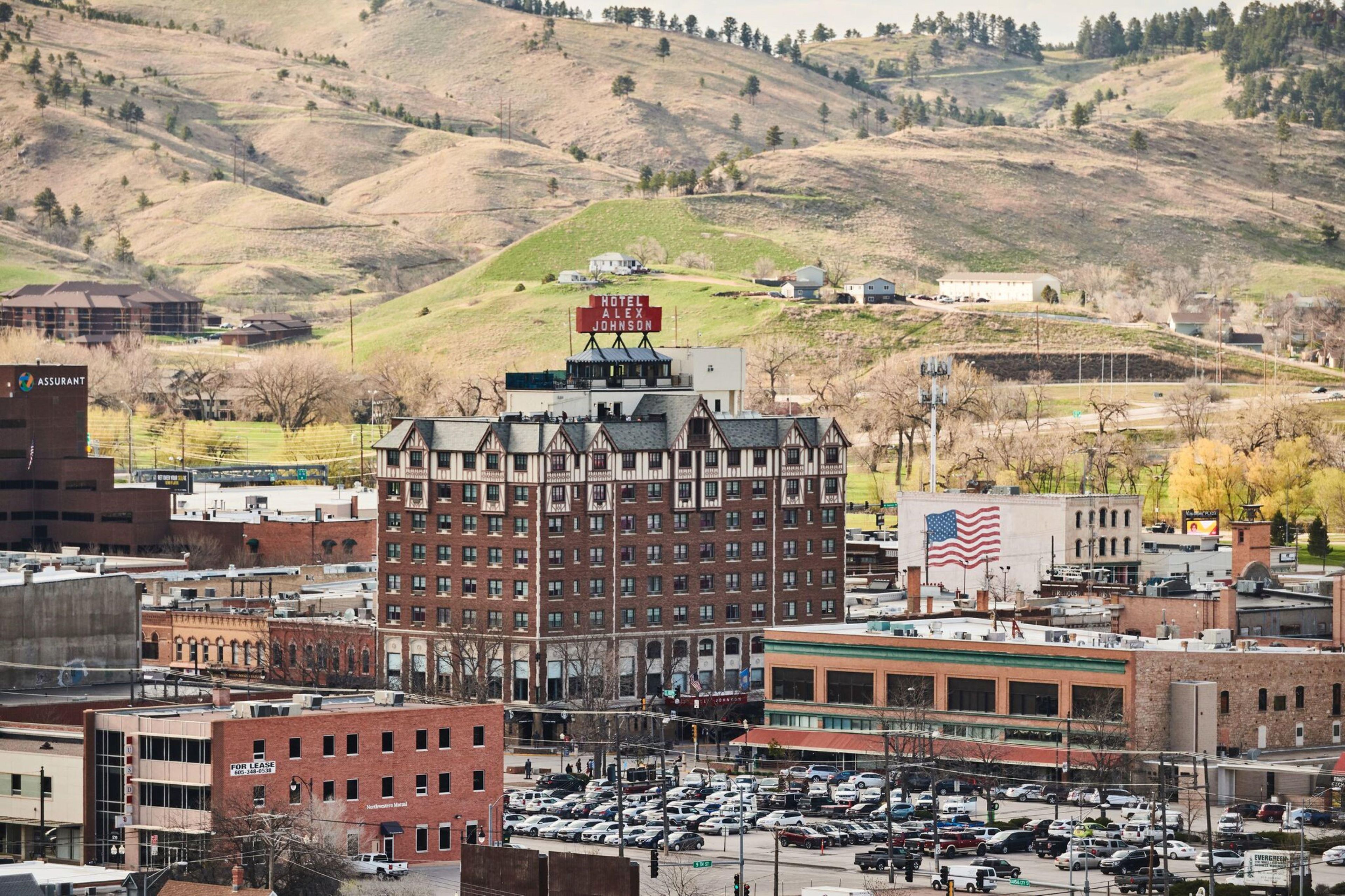 A multi-story building with a prominent sign for Hotel Alex Johnson.
