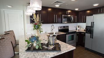 A modern kitchen with dark wood cabinets, stainless steel appliances, and a marble countertop.