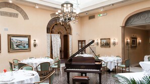 Un espace repas comprenant des tables, des chaises, un grand piano et un lustre.