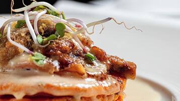Primer plano de un plato gourmet con varias capas de comida y adornos.