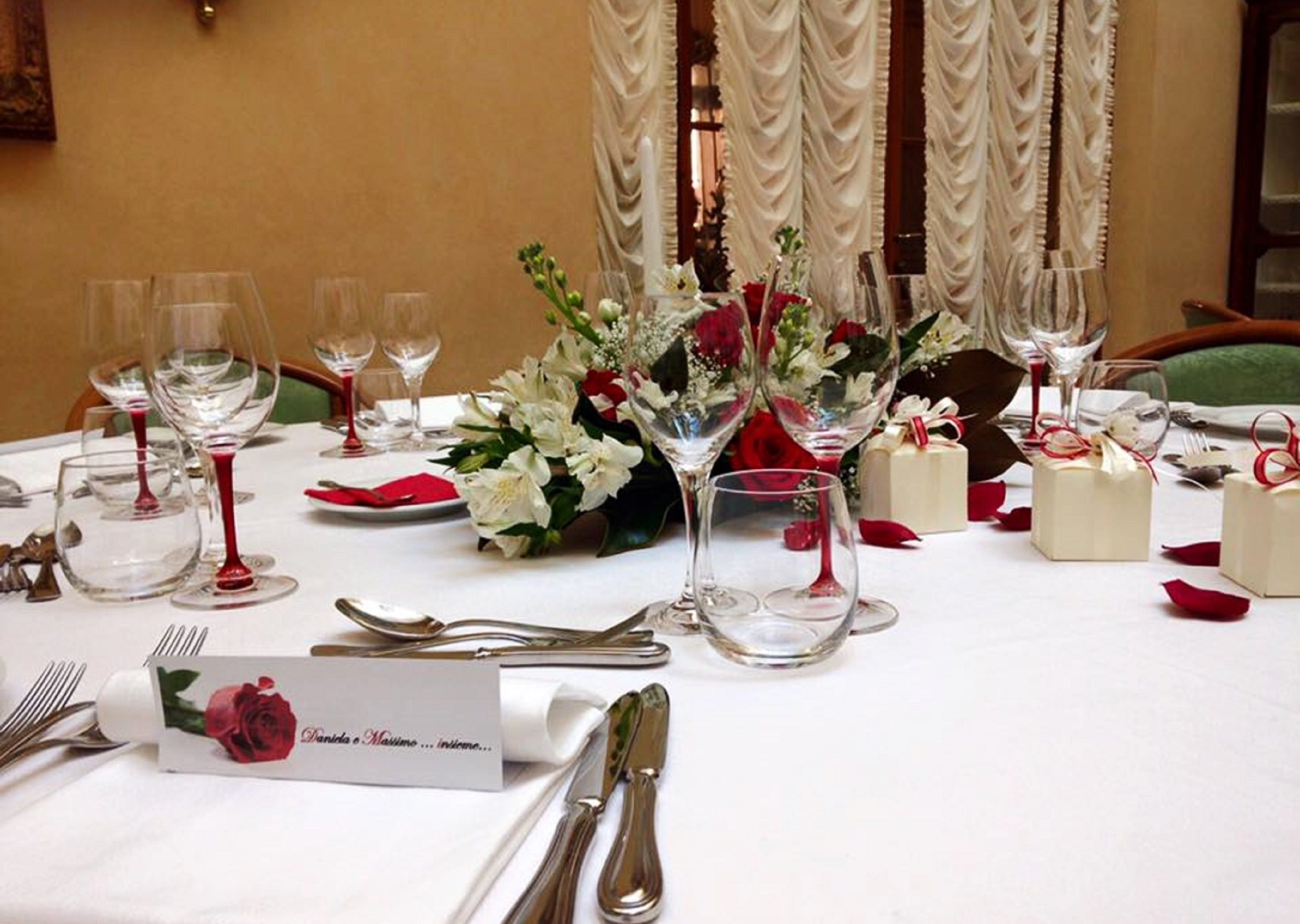 Et bord dækket op til en formel lejlighed med vinglas, bestik og blomsterarrangementer i midten.