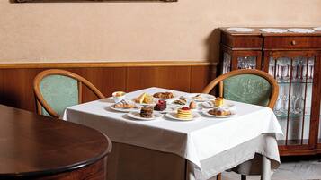 Un coin repas avec une table mise pour le repas, des chaises, un buffet contenant de la verrerie et un tableau encadré accroché au mur.