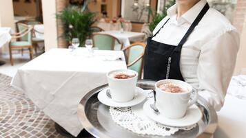 A waiter carrying a tray with two cups of hot chocolate.
