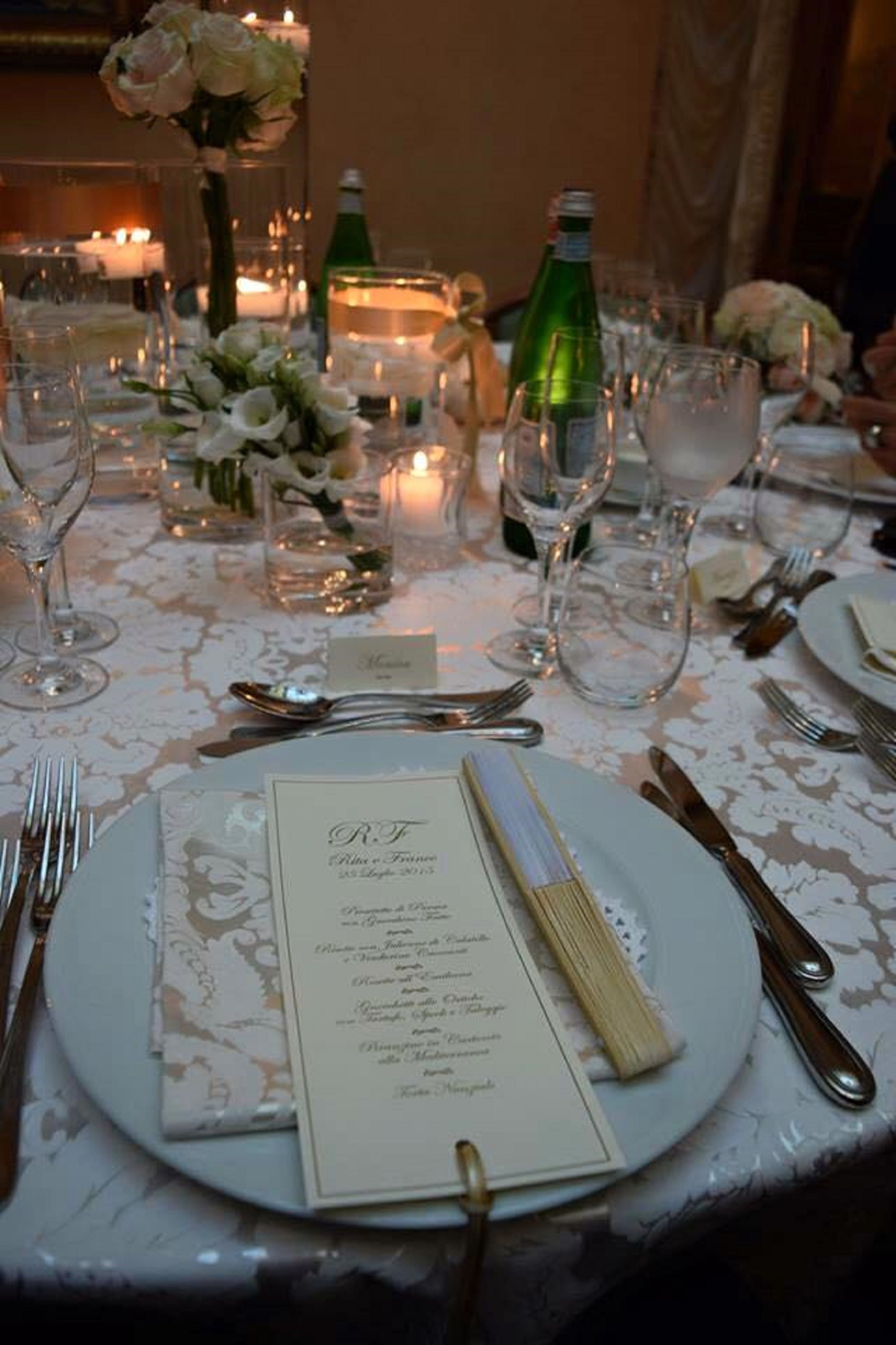 A table set for a formal dinner with a menu, glasses, and cutlery.