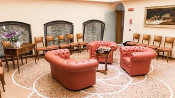 A hotel lobby with a round table, several chairs, a sofa, and a chess table.