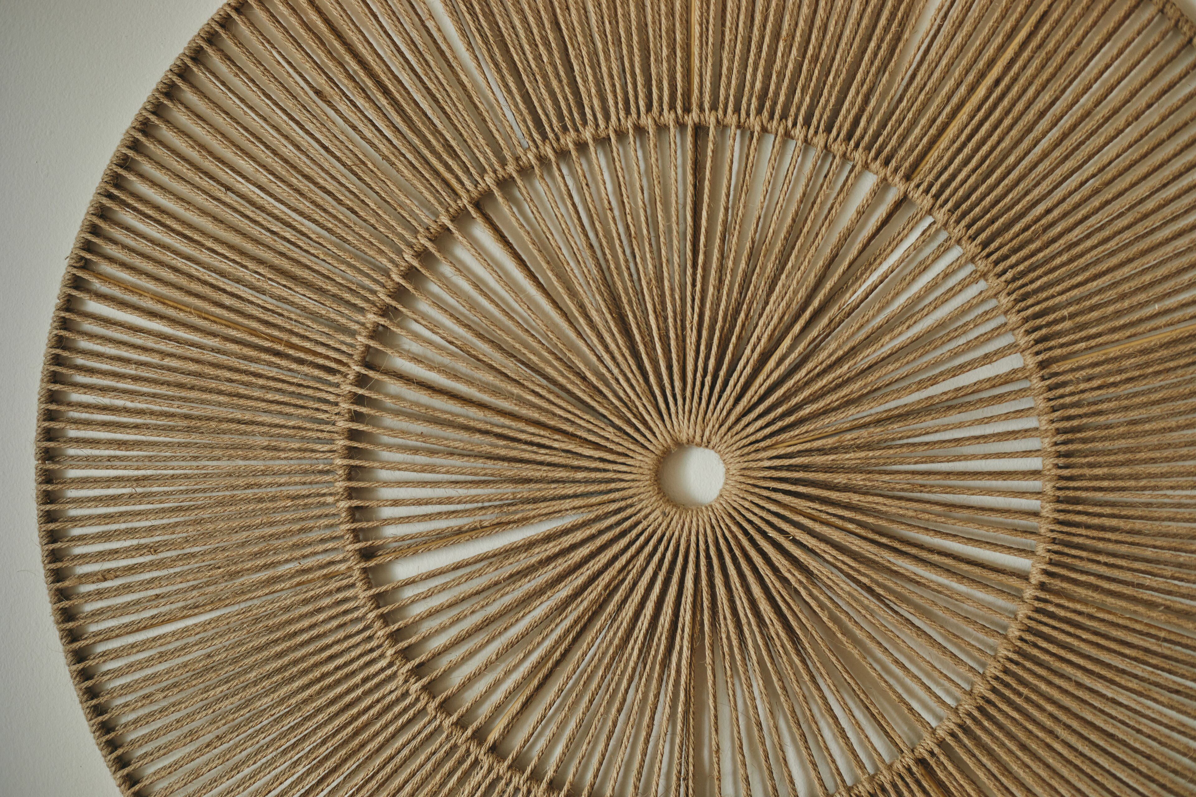 Une décoration murale circulaire ornée d’un motif radial de cordes.