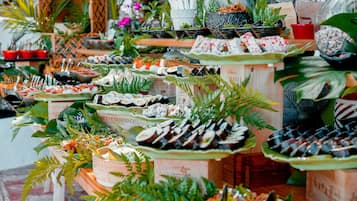 Variedad de alimentos exhibidos sobre mesas, rodeado de plantas y elementos decorativos.